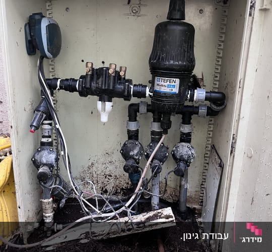 מערכת השקיה עם צינורות ושסתומים בגינה